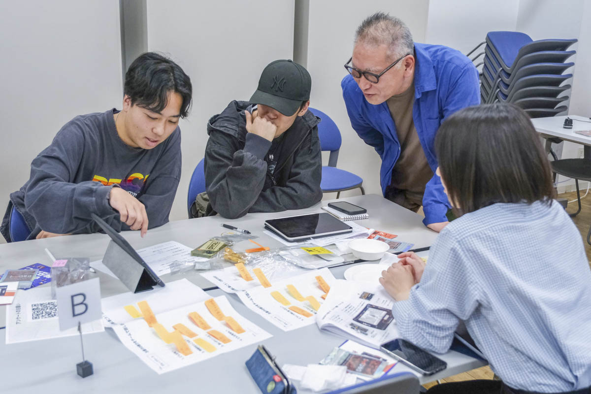 同じテーブルの学生や先生に、自分の絵コンテを紹介する京都芸術大学の学生